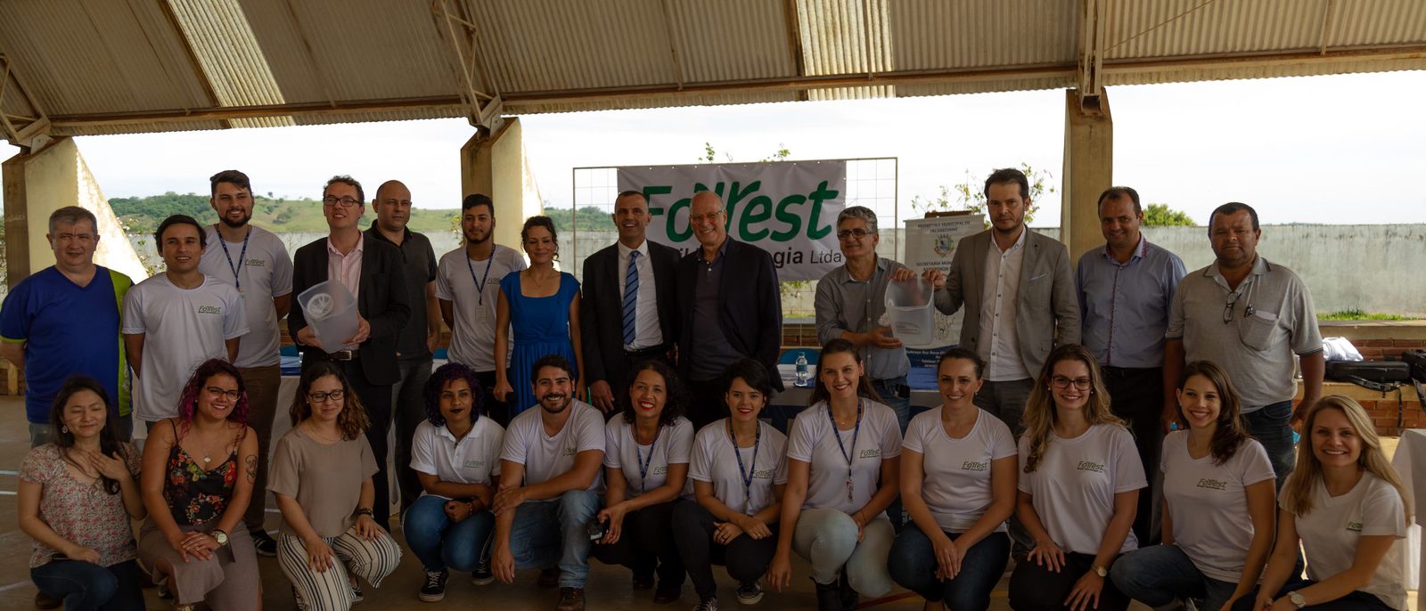 Equipe da Forrest reunida em ginásio, diante
      do banner da empresa