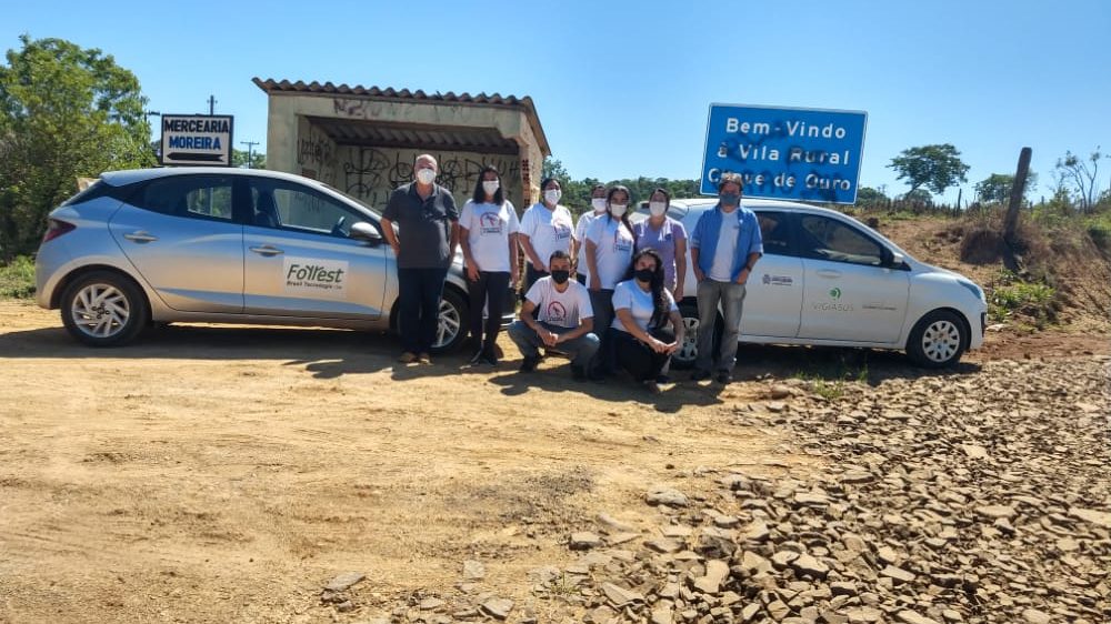 Equipe da Forrest reunida ao lado dos
        veículos, na entrada de uma vila rural